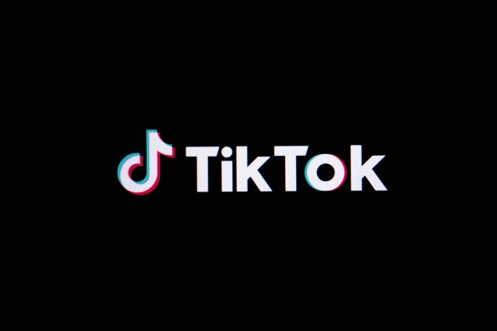 Logotipo do TikTok em branco com efeito de desfoque vermelho e azul, sobre fundo preto